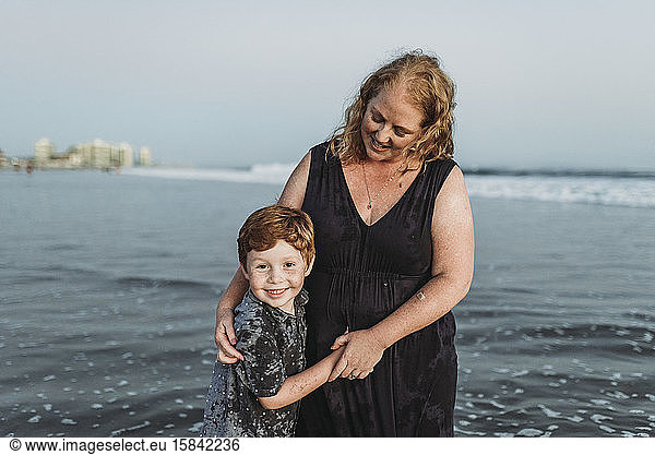 Portrait of son smiling with mother at dusk in the ocean at beach
