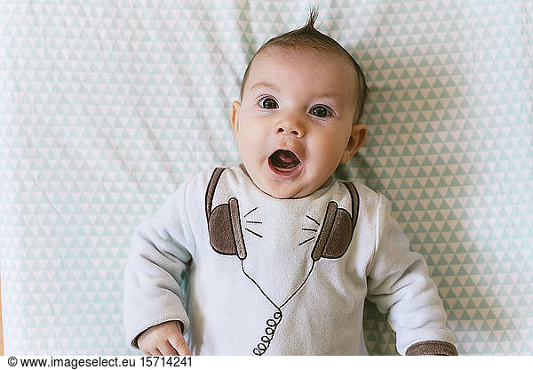 Portrait of surprised baby girl with appliqued headphones on pyjama