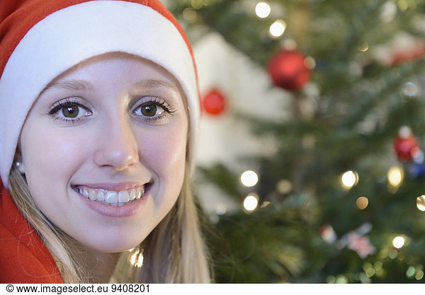 Portrait of teenage girl in front of christmas tree  smiling