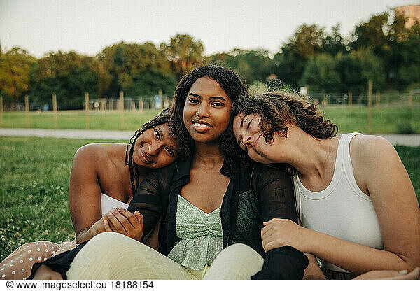 Portrait of teenage girl sitting amidst female friends at park