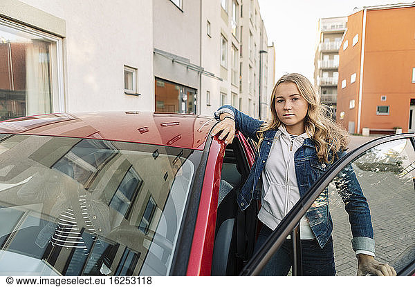 Portrait of teenage girl standing by car