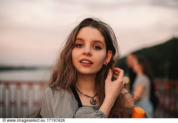 Portrait of teenage girl standing on bridge at sunset during summer