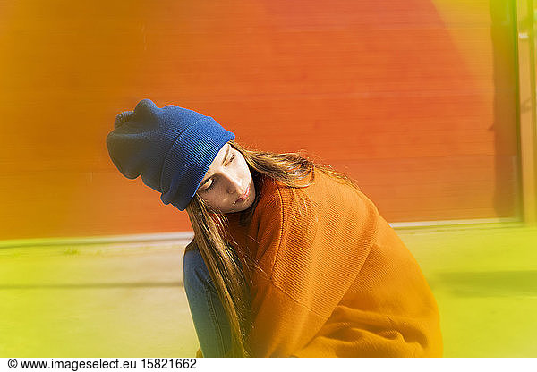 Portrait of teenage girl wearing blue woolly hat and orange sweater