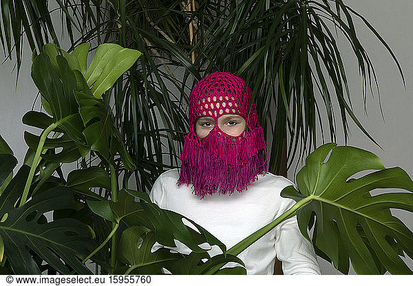 Portrait of teenage girl wearing crocheted pink headdress between house plants