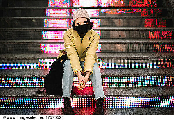 Portrait of teenage girl wearing face mask sitting on steps