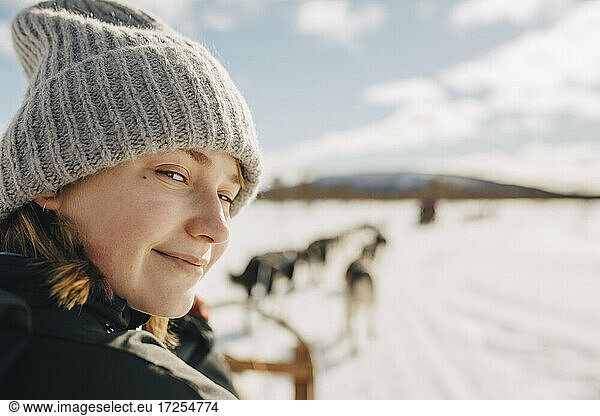 Portrait of teenage girl wearing knit hat doing dogsledding during winter