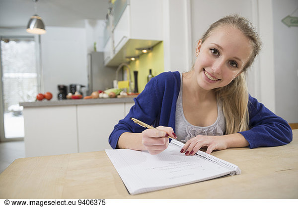 Portrait of teenage girl writing notes  smiling