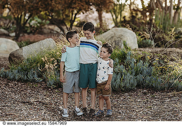 Portrait of three brothers smiling at each other in cactus garden