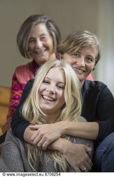 Portrait of three generation females sitting in a row at home