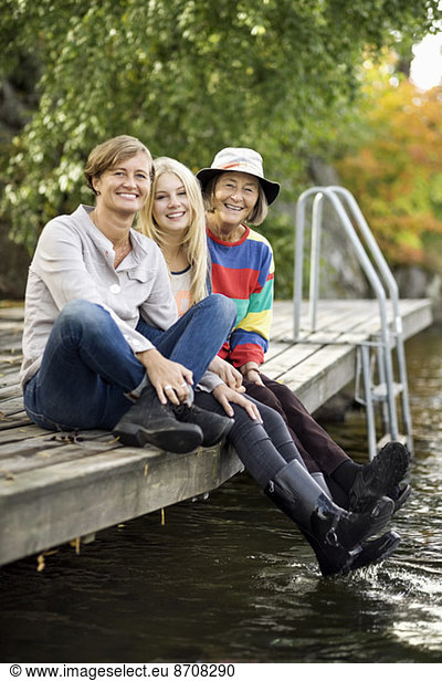 Portrait of three generation females sitting on pier
