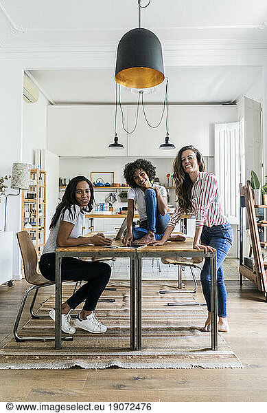 Portrait of three happy women at table at home