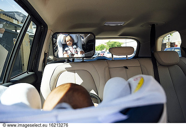 Portrait of toddler sitting in child's seat in a car