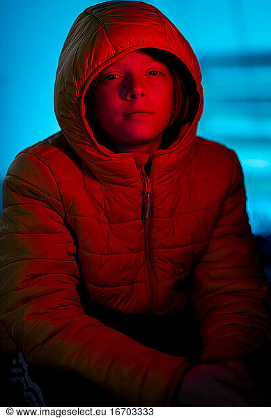 Portrait of Tween covered in red light with blue light in background