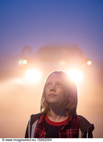 Portrait of tween looking up backlit by truck lights