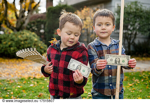 Portrait of two brothers holding allowance from raking leaves
