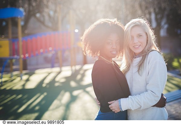 Portrait of two female friends hugging in park