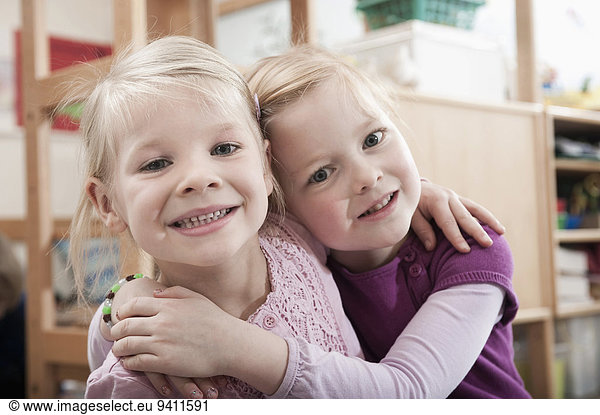 Portrait of two little girls  best friends  side by side in kindergarten