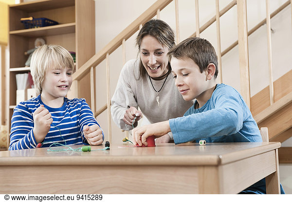 Portrait of two playing boys and female childcare assistant