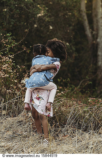 Portrait of two sisters hugging in backlit field