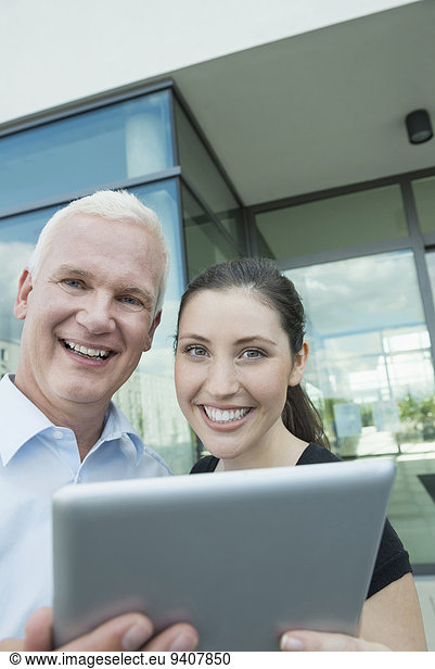 portrait of two smiling colleagues with tablet computer