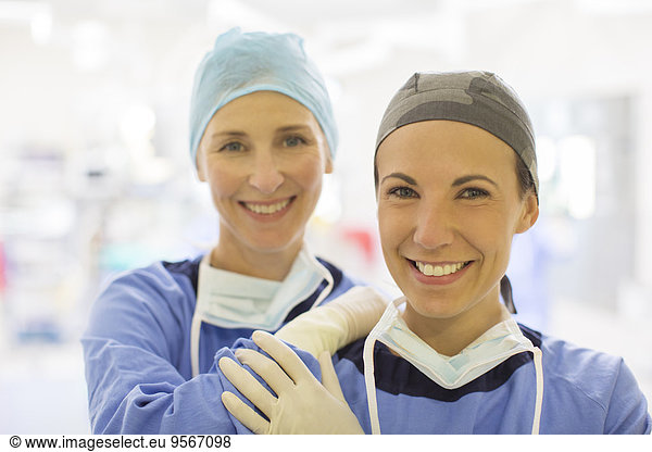 Portrait of two smiling female doctors wearing surgical caps in operating theater