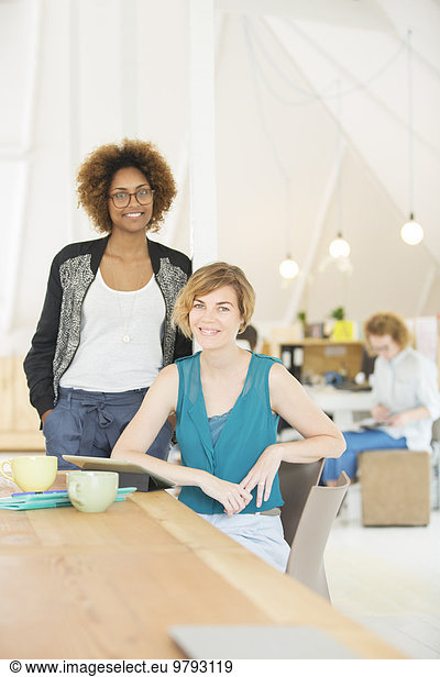Portrait of two smiling office workers at desk