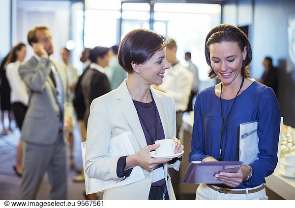 Portrait of two smiling women  talking in lobby of conference center during coffee break