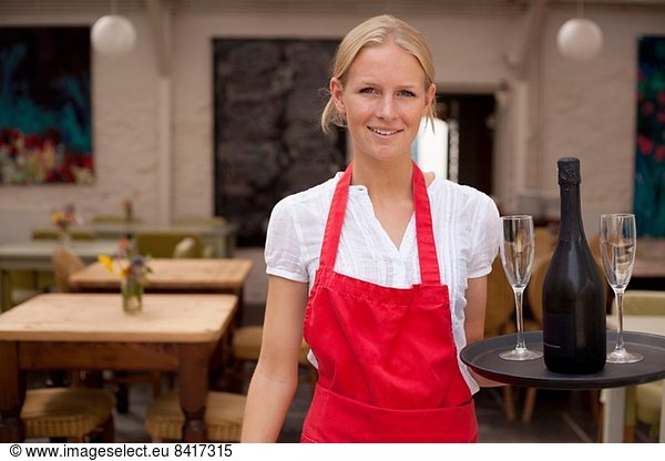 Portrait of waitress with tray of wine and glasses in cafe