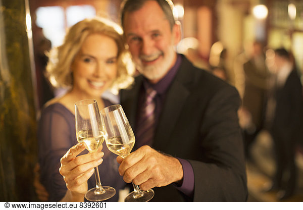 Portrait of well dressed couple toasting champagne glasses in theater lobby