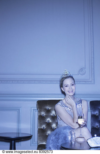 Portrait of well dressed woman wearing tiara and drinking champagne