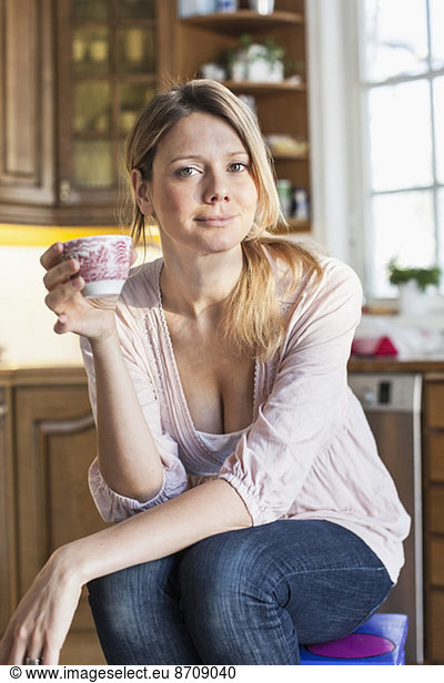 Portrait of woman holding coffee cup in kitchen