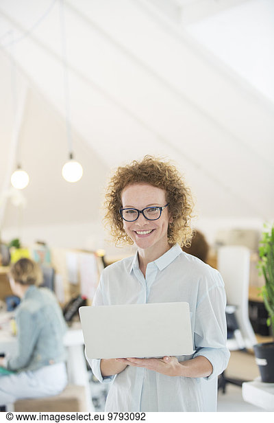 Portrait of woman holding laptop at office