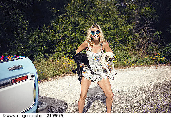 Portrait of woman in sunglasses carrying pugs on street