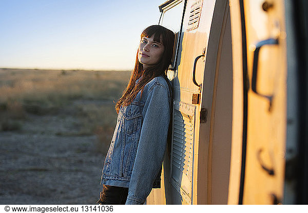 Portrait of woman leaning on camper van