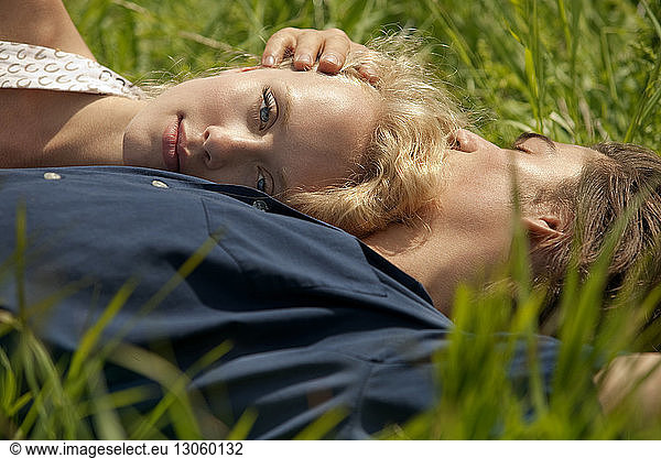 Portrait of woman leaning on man's chest while lying in grass field