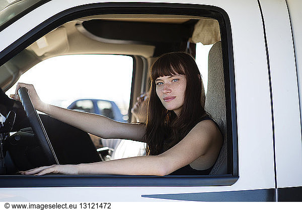 Portrait of woman looking through window while sitting in camper van