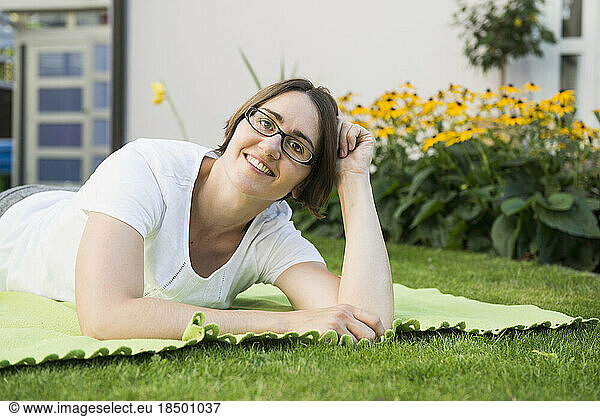 Portrait of woman lying on a blanket at garden of her house  Bavaria  Germany