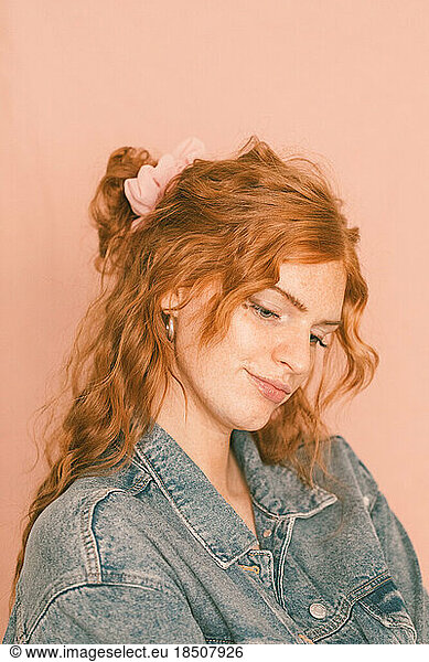Portrait of woman smiling in denim jacket with pink scrunchie in