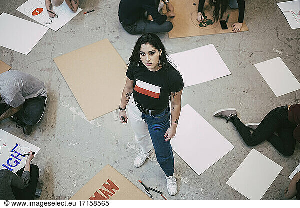 Portrait of woman standing while male and female activist preparing signboards in building