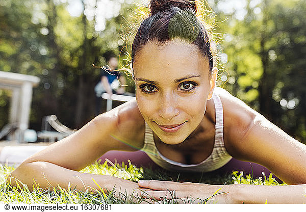 Portrait of woman stretching on grass near a fitness trail