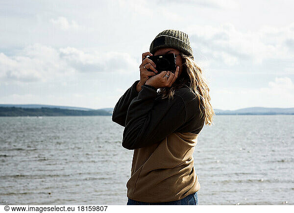 portrait of woman taking a photograph at the beach