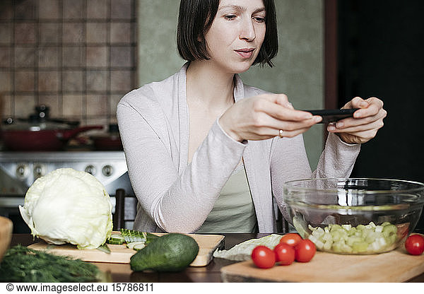 Portrait of woman taking photo of salad with smartphone