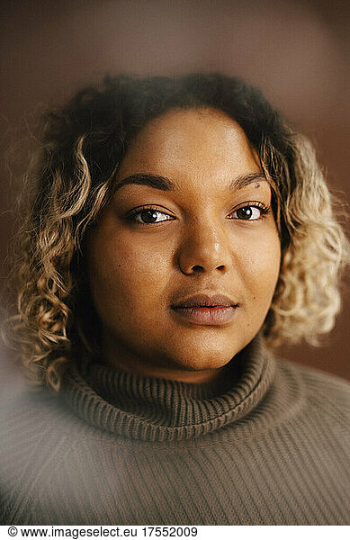 Portrait of woman wearing turtleneck against brown background