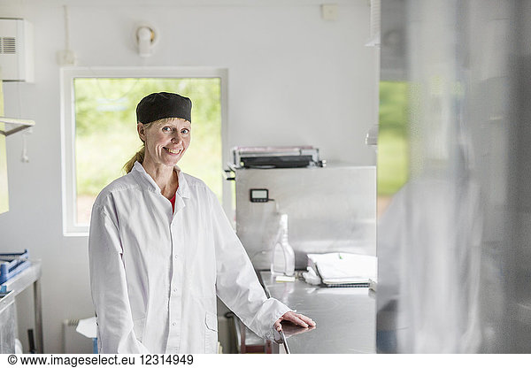 Portrait of woman wearing white coat in commercial kitchen