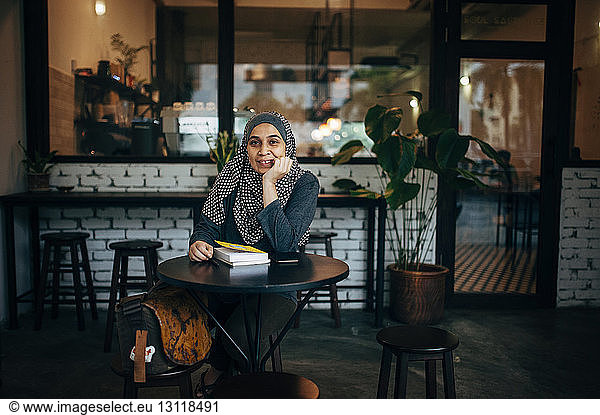 Portrait of woman with books sitting in cafe