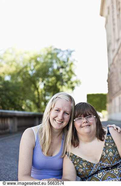 Portrait of woman with down syndrome sitting together with friend