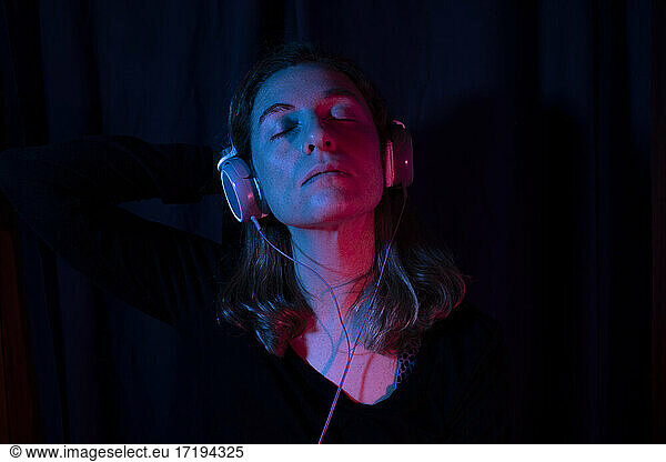 Portrait of woman with headphones set with red and blue neon lights