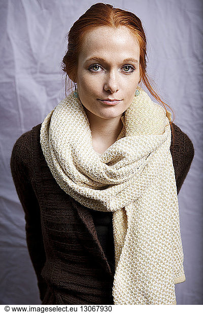 Portrait of woman with scarf standing against white fabric