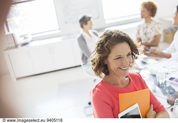 Portrait of woman with tablet in office  colleagues in background
