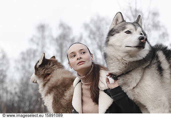 Portrait of woman with two huskies watching something